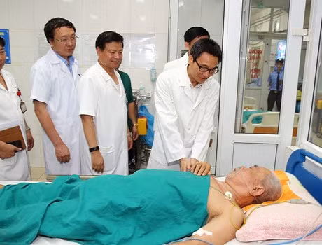 Phó Thủ tướng Vũ Đức Đam hỏi thăm một bệnh nhân cao tuổi mắc sốt xuất huyết đang điều trị tại Bệnh viện Nhiệt đới Trung ương. Ảnh: VGP/Đình Nam.