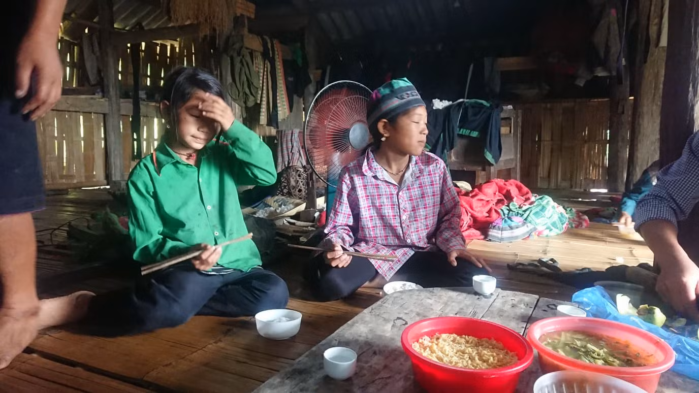 Ly Thị Óng (áo xanh) và bữa cơm với mỳ tôm của những đứa trẻ người La Chí. (Ảnh Nguyễn Toan)