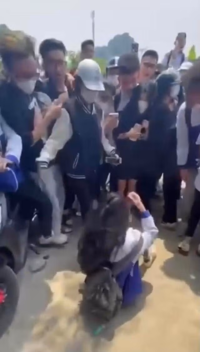 Trong khi bạn bị đánh, các em học sinh khác hò reo và lấy điện thoại quay lại clip. Ảnh cắt từ clip